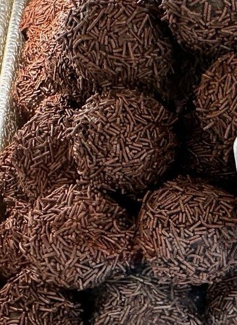 Close-up of many chocolate brigadeiros, a Brazilian candy, covered in chocolate sprinkles.