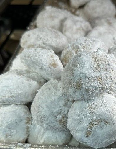 Snowball cookies dusted with powdered sugar, stacked on a tray.