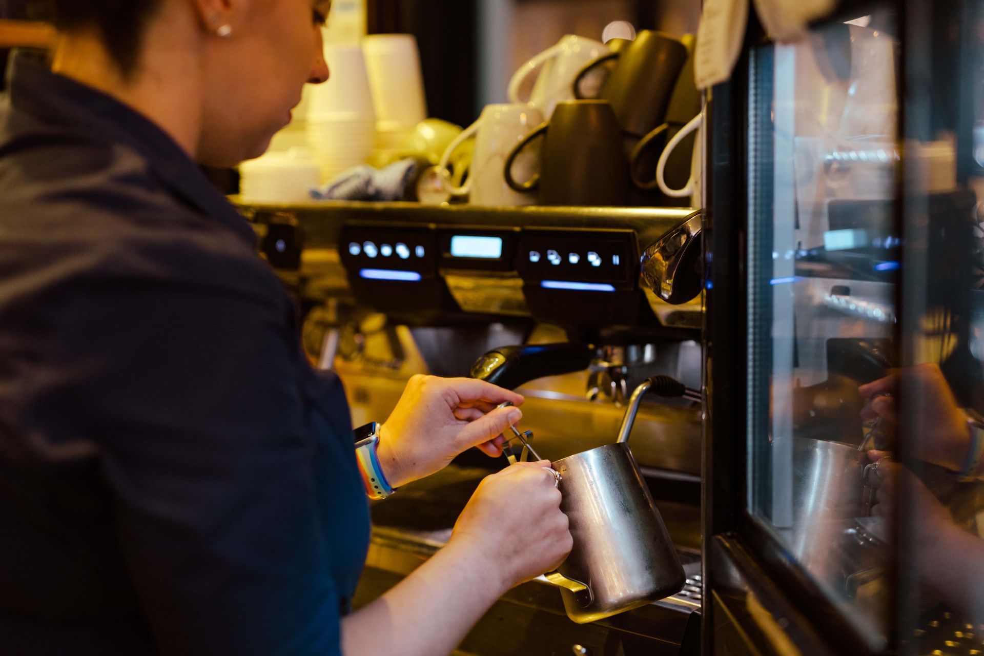 A woman is pouring milk into a cup of coffee