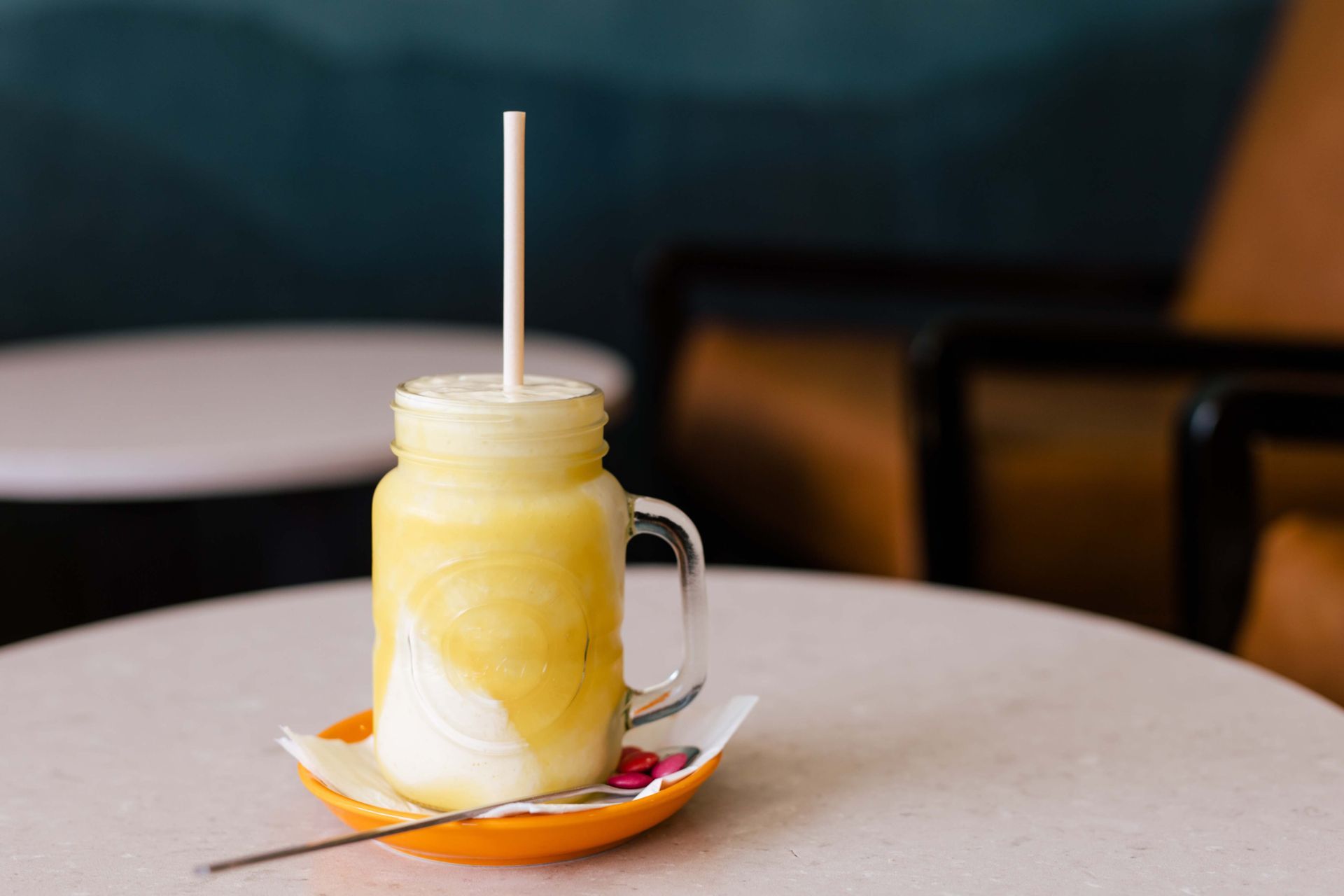 A yellow drink in a mason jar with a straw