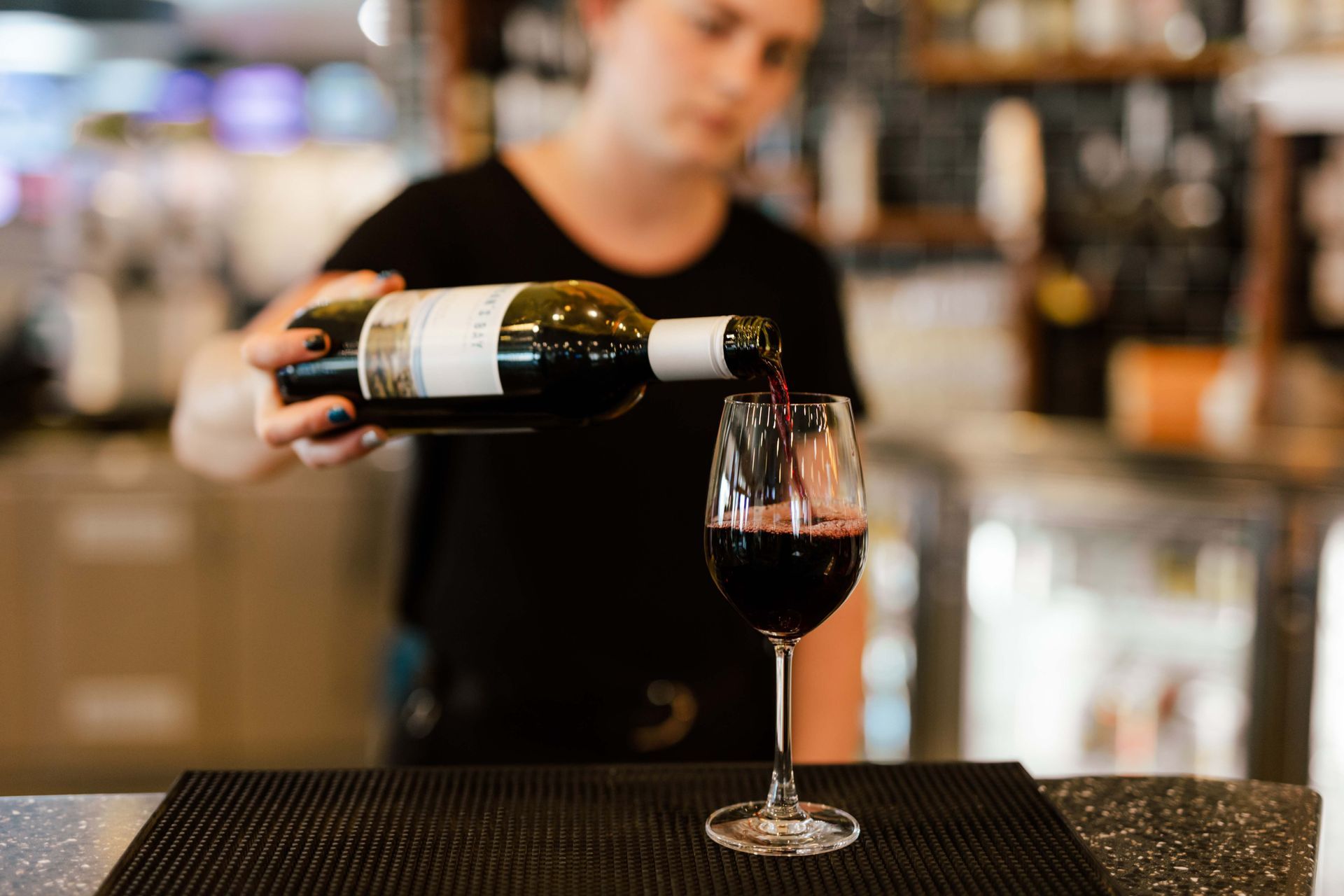 A woman is pouring a bottle of wine into a glass