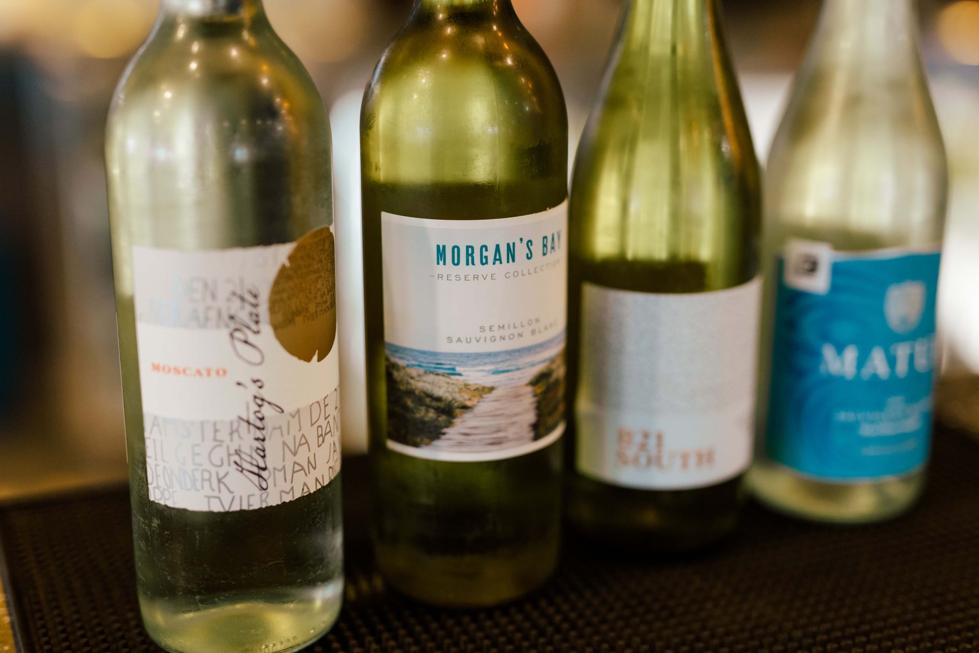 Several bottles of wine are lined up on a bar
