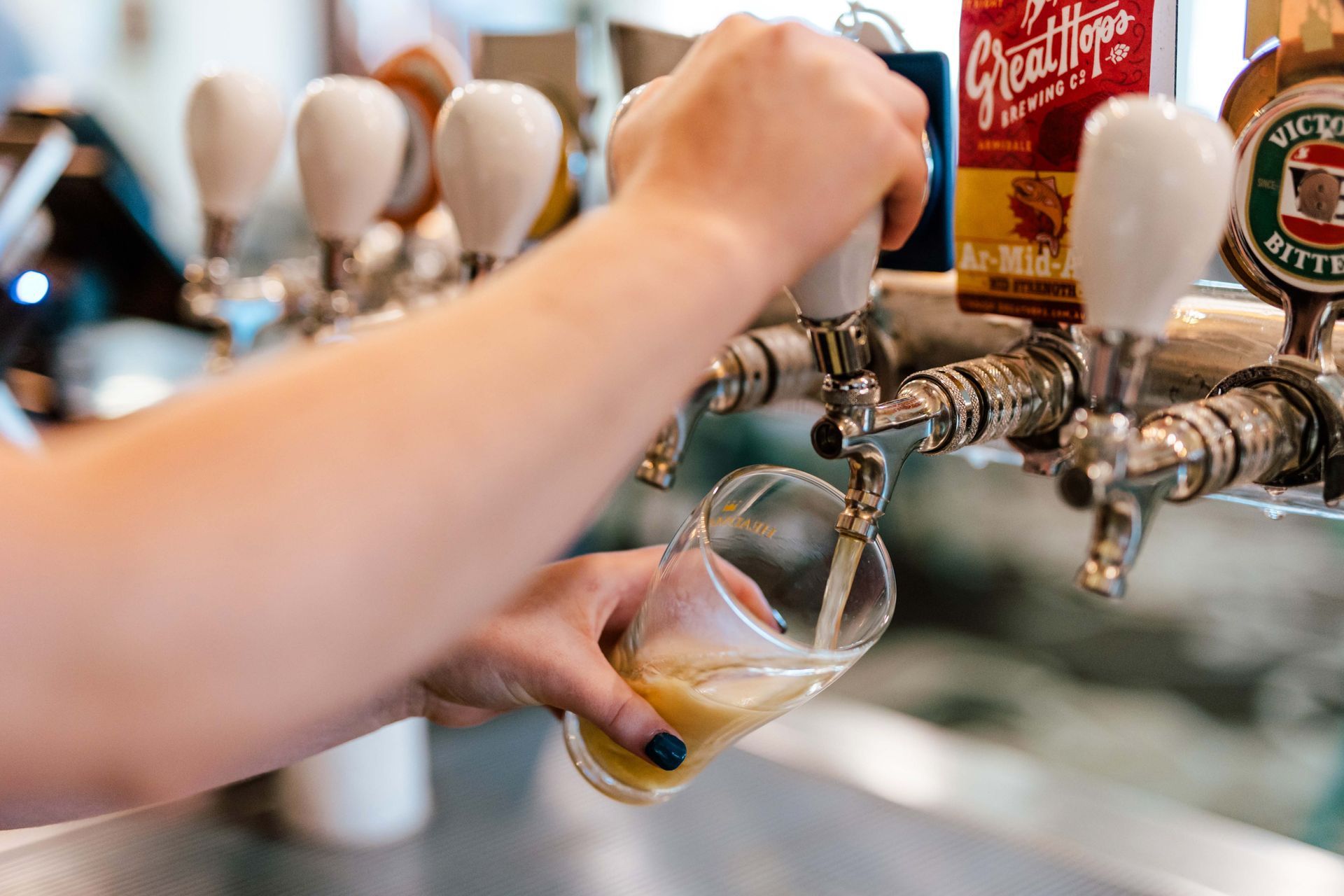 A person is pouring a glass of beer from a tap