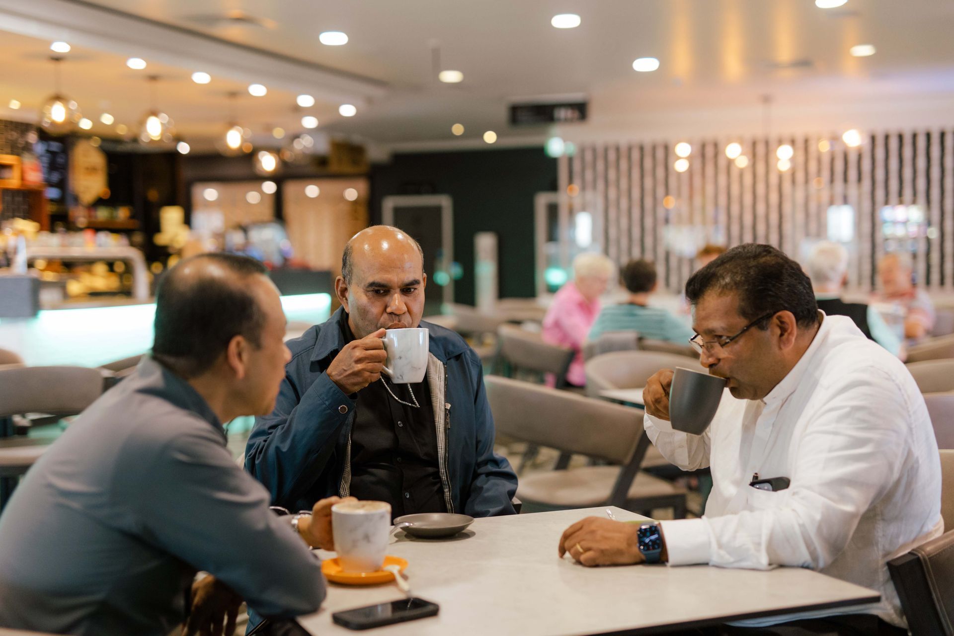 A group of men are sitting at a table drinking coffee