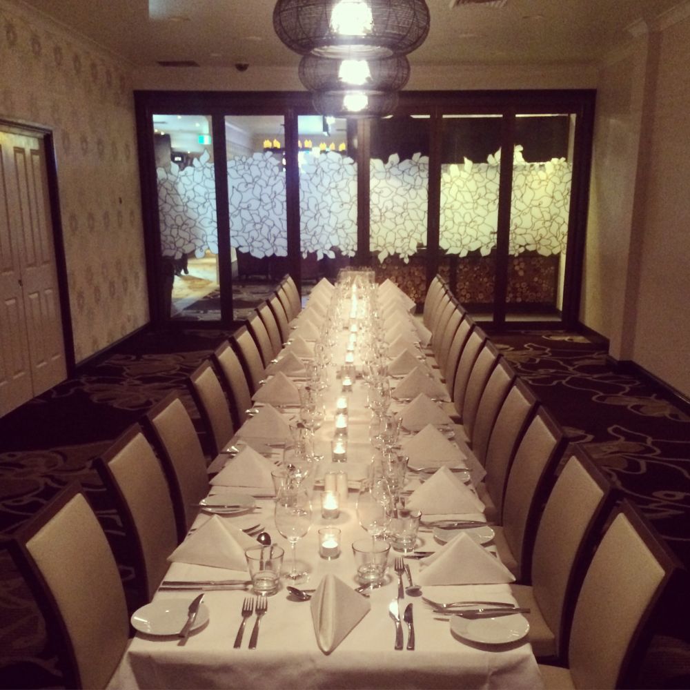 A long table with a white table cloth and candles on it