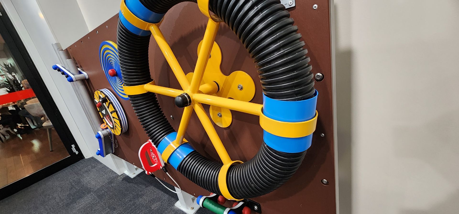 A wheel made out of pipes is hanging on a wall.