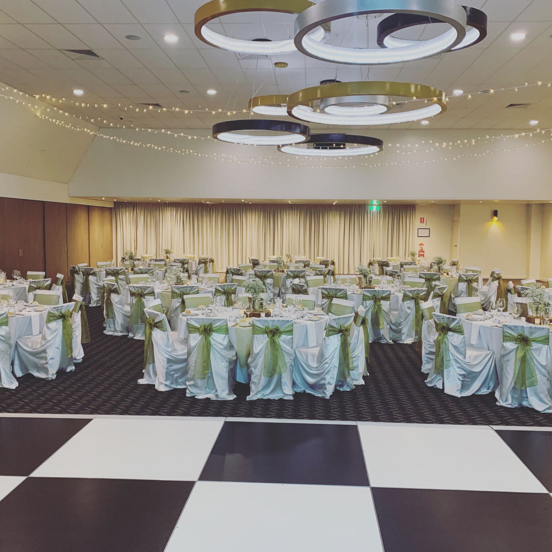 A large room with tables and chairs set up for a wedding reception