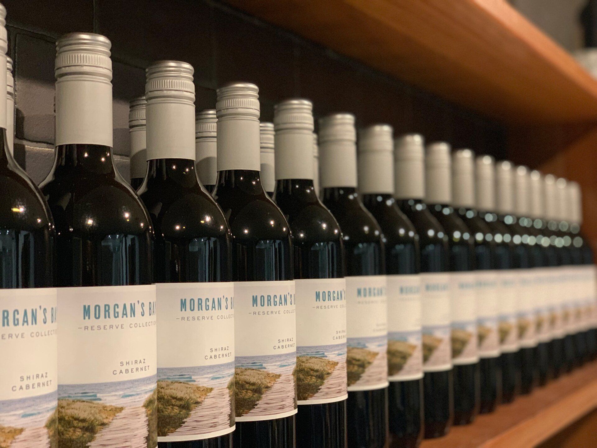 Several bottles of Morgan 's wine are lined up on a shelf