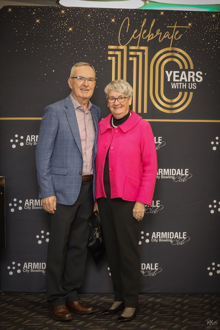 A man and woman standing in front of a backdrop that says Celebrate 110 years with us