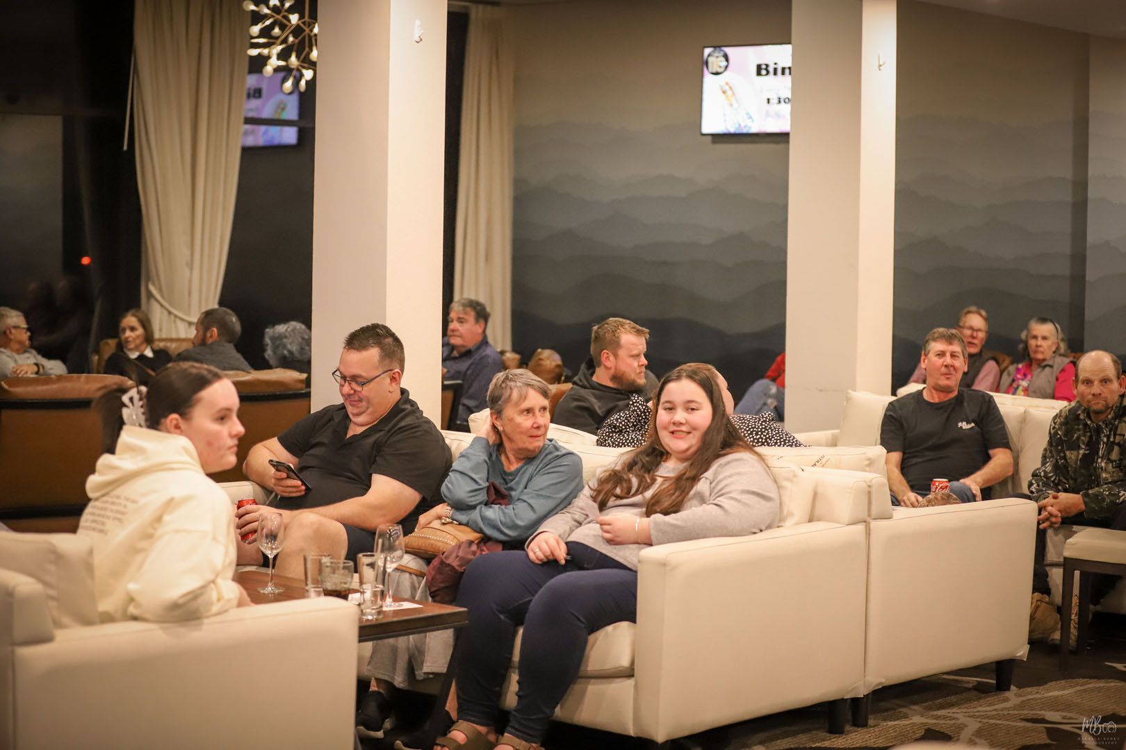 A group of people are sitting on white couches in a room