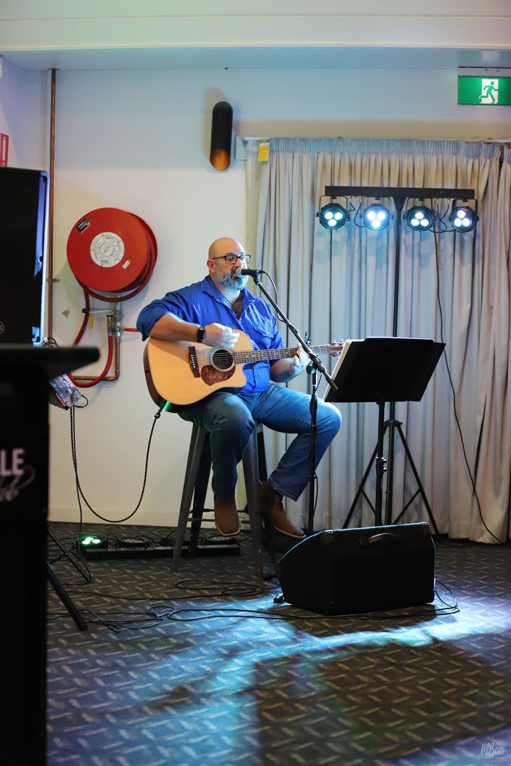 A man singing into a microphone while playing a guitar