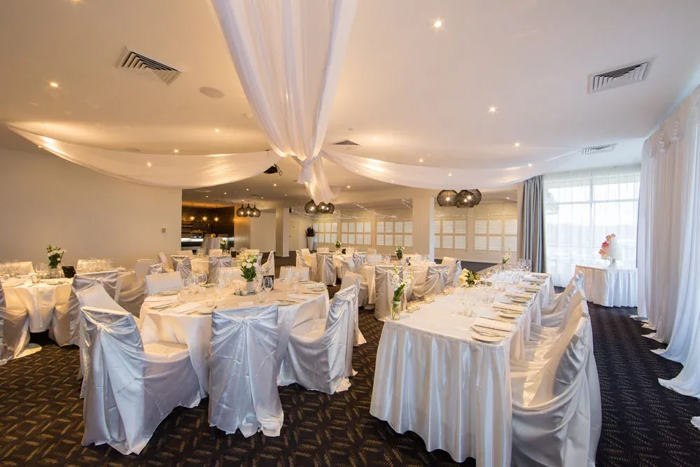 A large room with tables and chairs set up for a wedding reception.