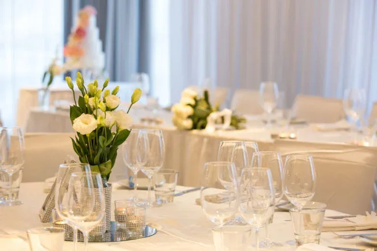 A table set for a wedding reception with a vase of flowers on it.