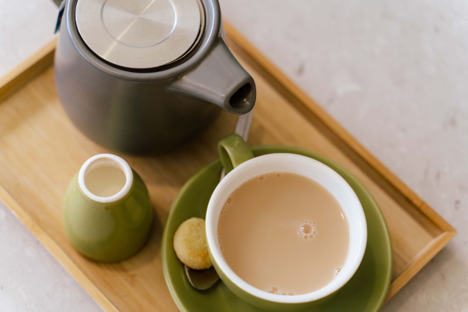 A cup of tea on a saucer next to a teapot