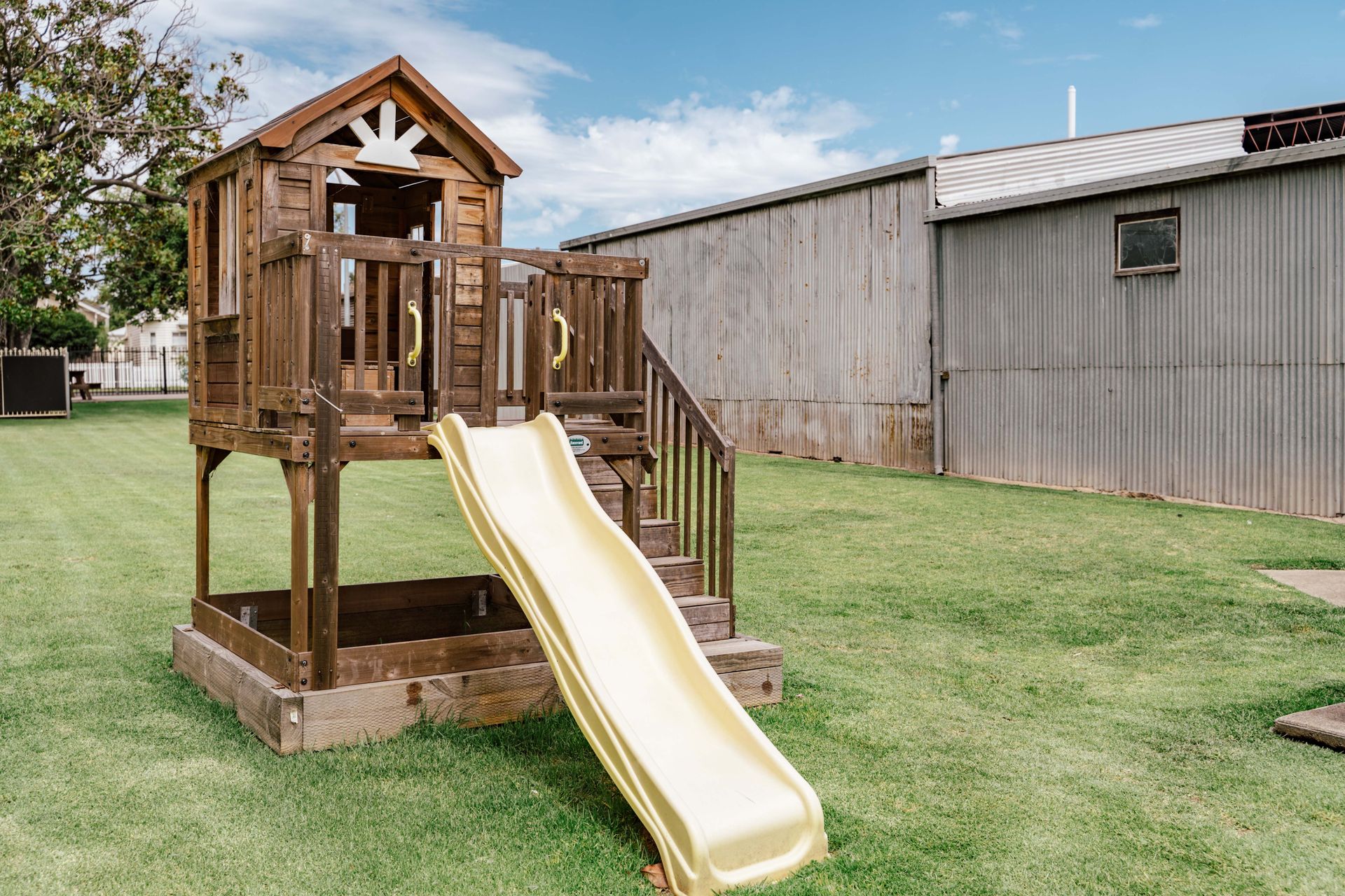 A wooden playhouse with a slide and stairs
