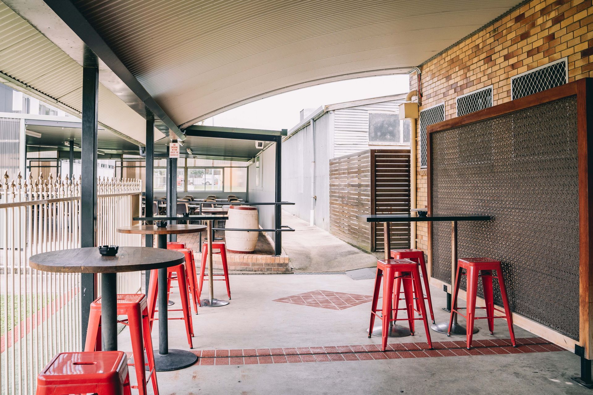 A covered outdoor area with tables and red stools