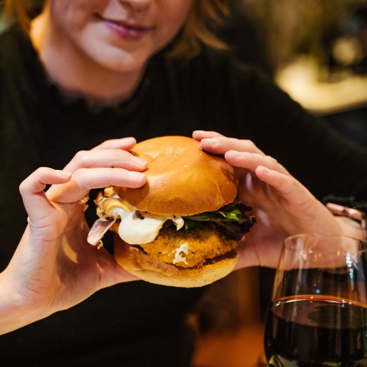 A woman is holding a hamburger in her hands