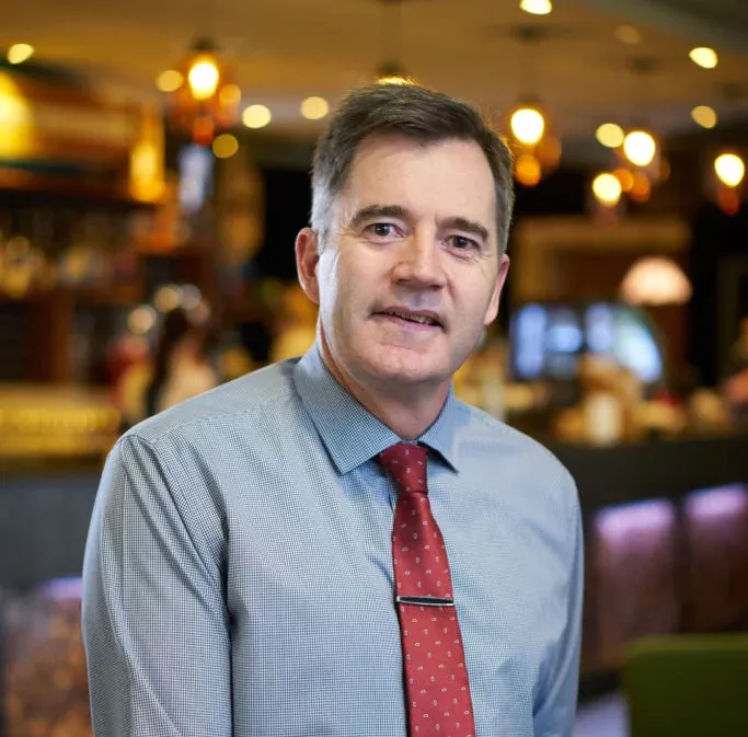 A man (Graeme) wearing a blue shirt and a red tie