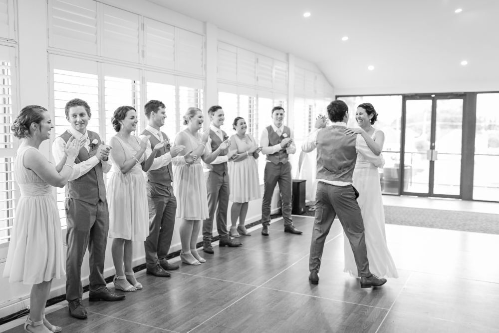 A bride and groom are dancing in front of their wedding party.
