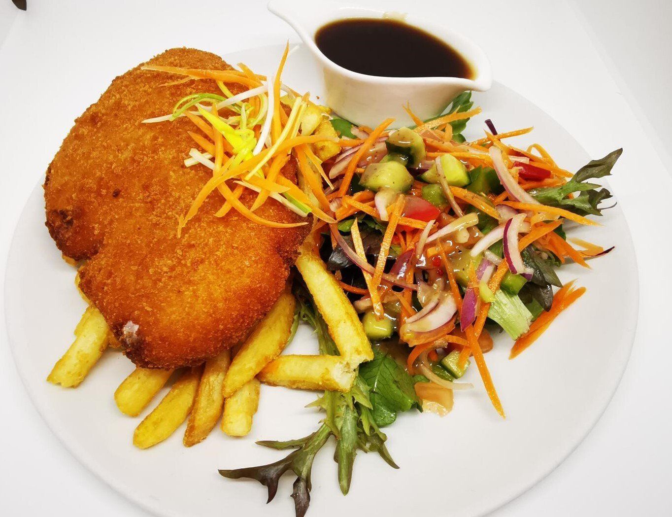 A plate of food with schnitzel, french fries and a salad