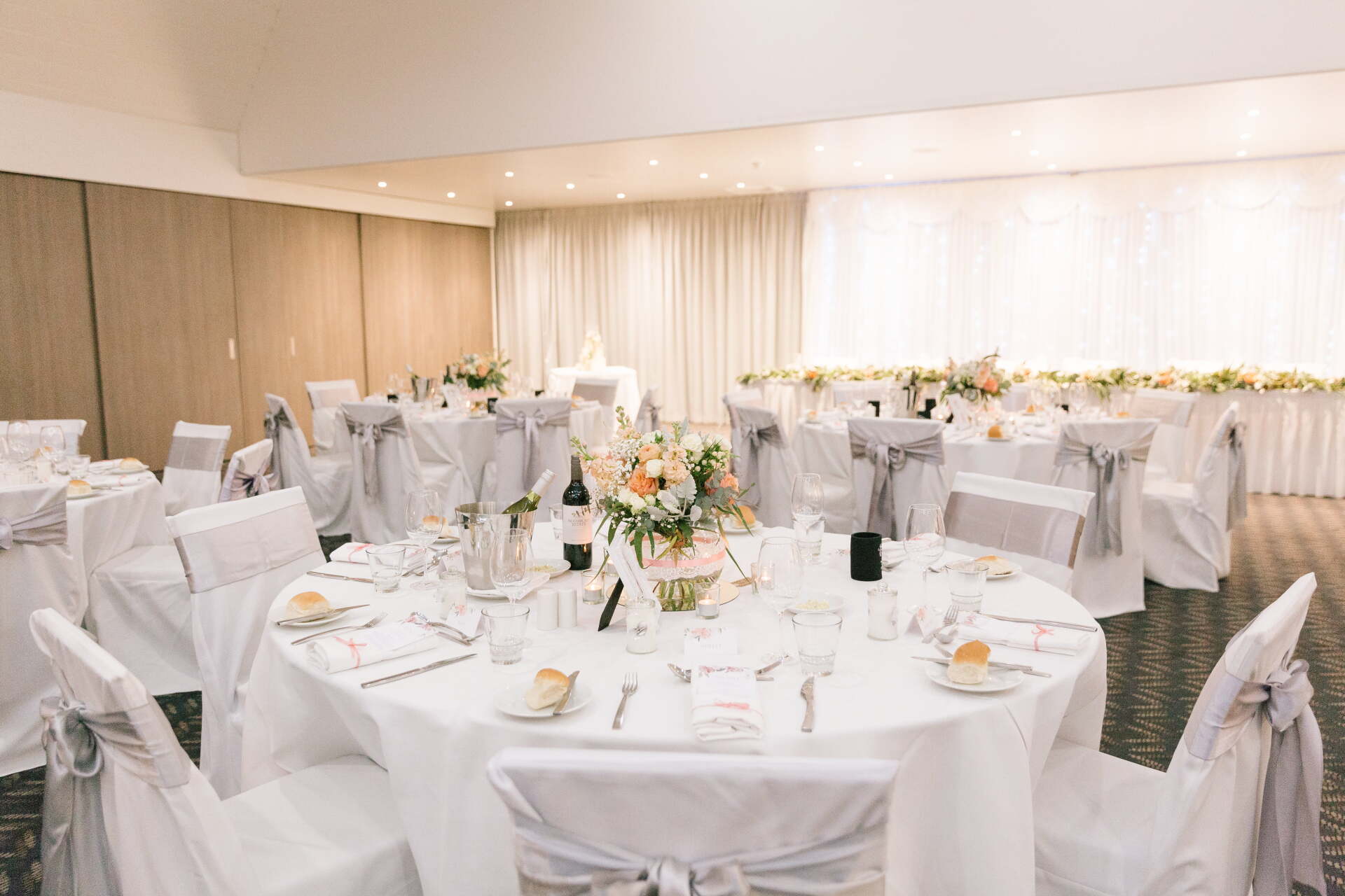 A room with tables and chairs set up for a wedding reception