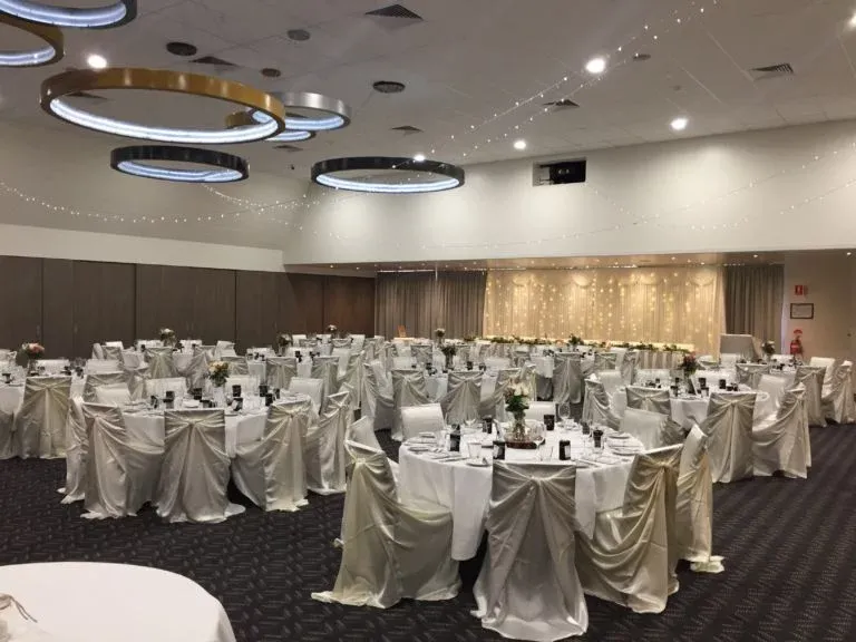 A large room with tables and chairs set up for a wedding reception.