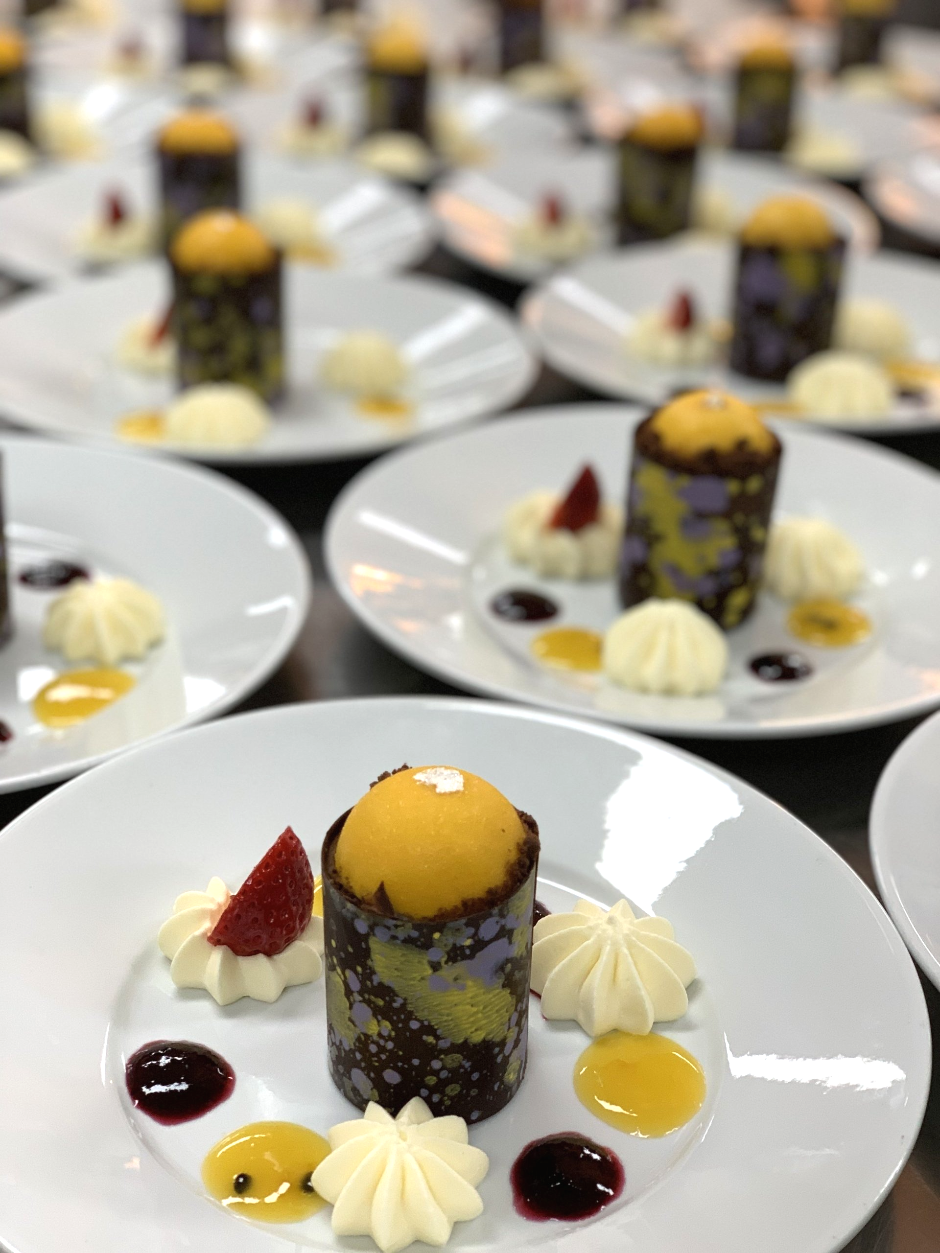 A row of white plates with desserts on them