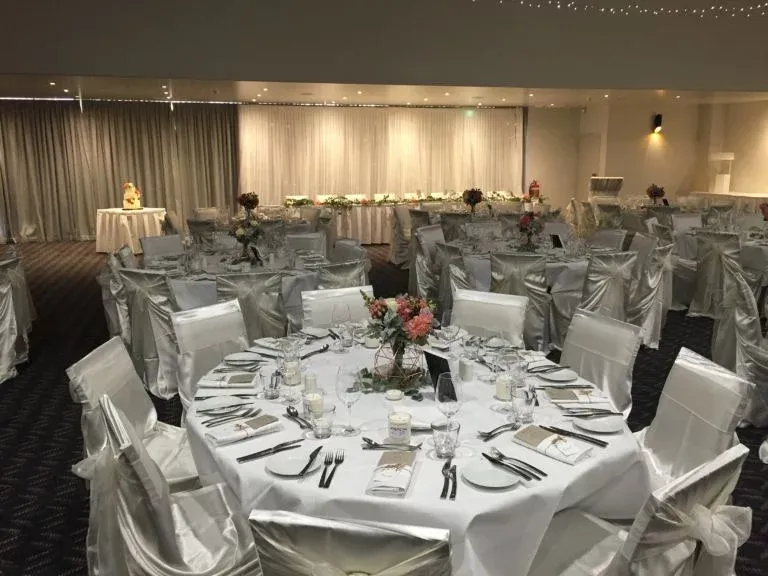 A large room with tables and chairs set up for a wedding reception.