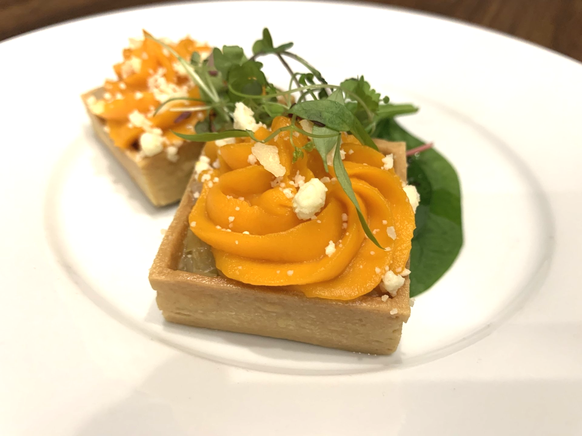 Food on a white plate with a green leaf on the side