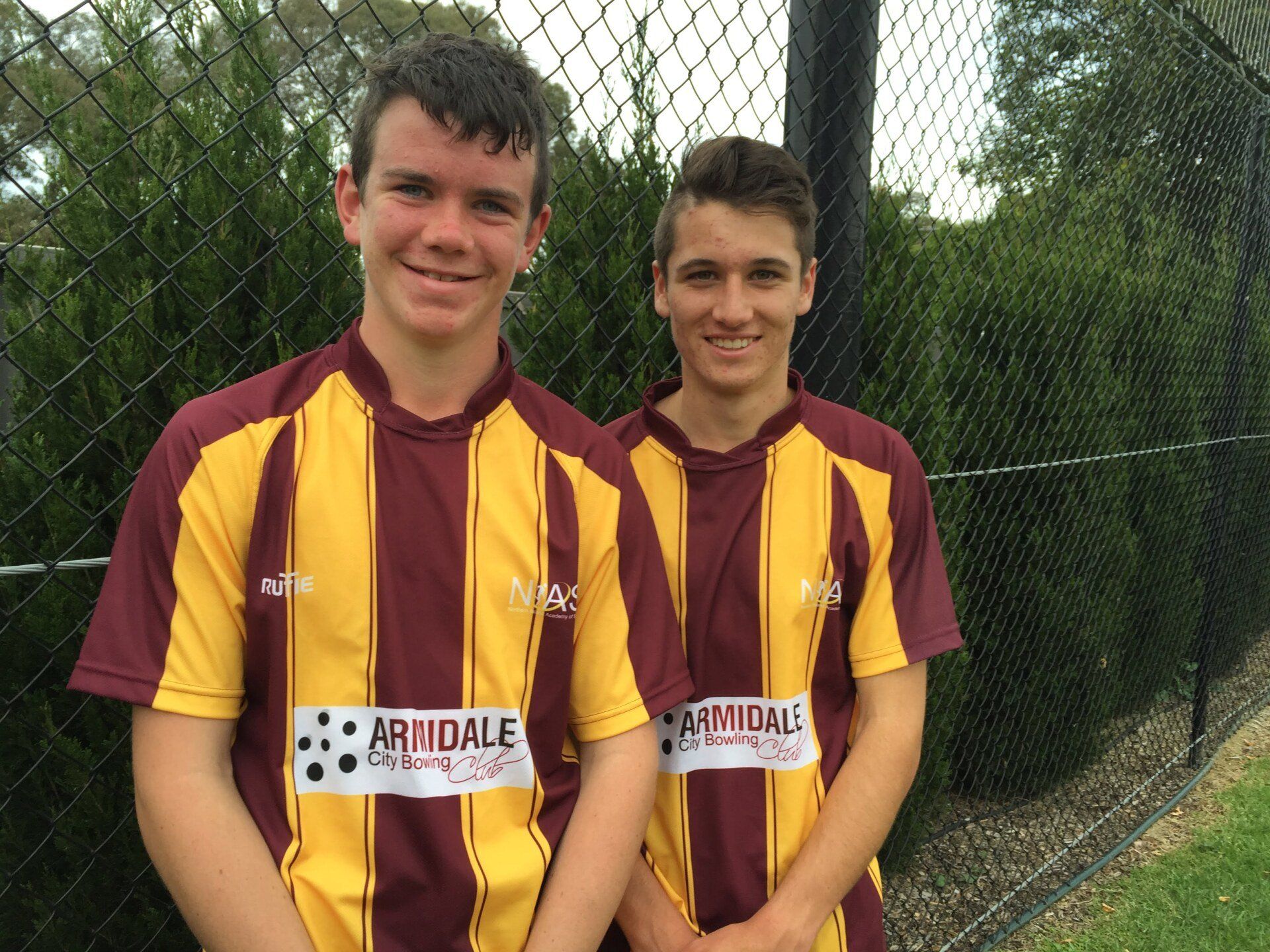 Two boys wearing maroon and yellow striped shirts