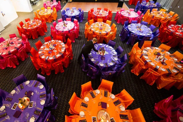 A large room filled with tables and chairs covered in different colors