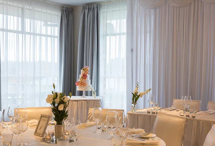 A room with tables and chairs set up for a wedding reception