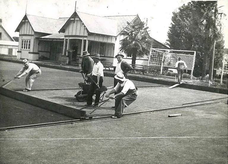 A black and white photo of a group of men on a bowling green