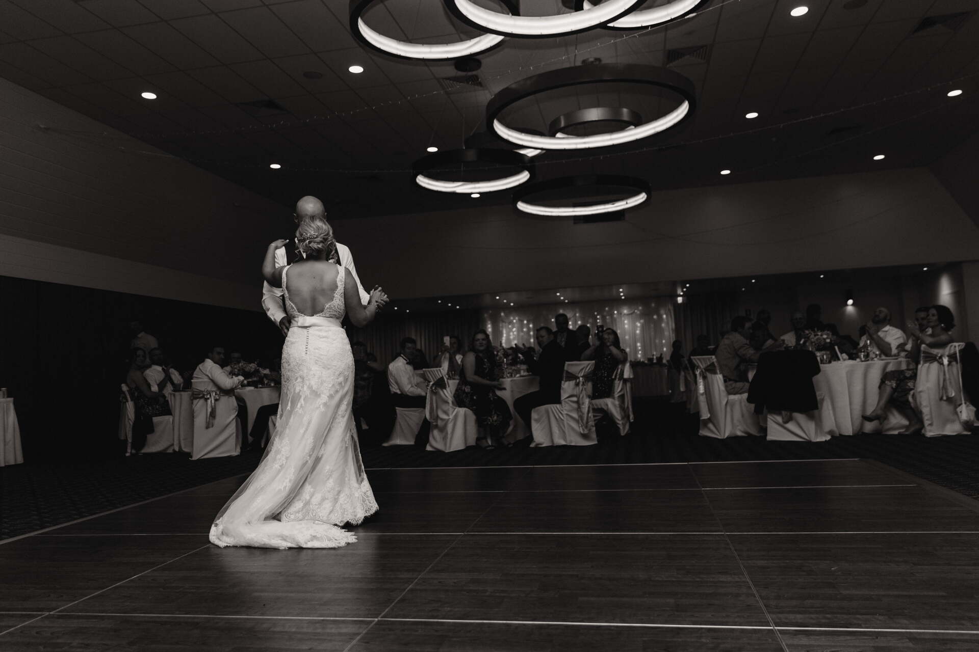 A bride and groom are dancing their first dance at their wedding reception.
