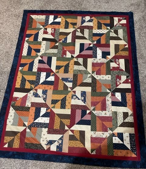 A Colorful Quilt With A Blue Border Is On A Carpet - Cheyenne, WY - Sewing Center of Cheyenne