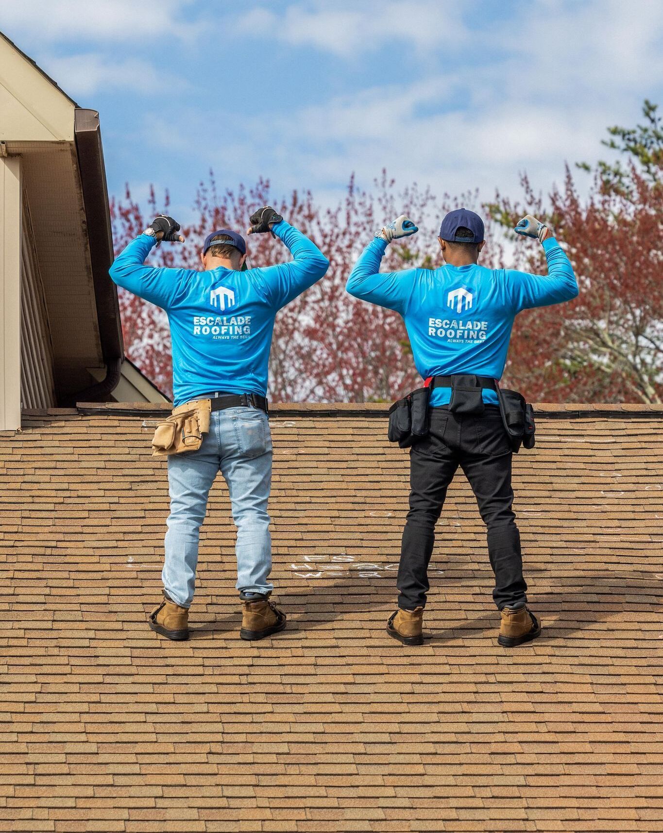 Aerial view of a large, multi-gabled house with a stone facade, gray roof, and lush green lawn.
