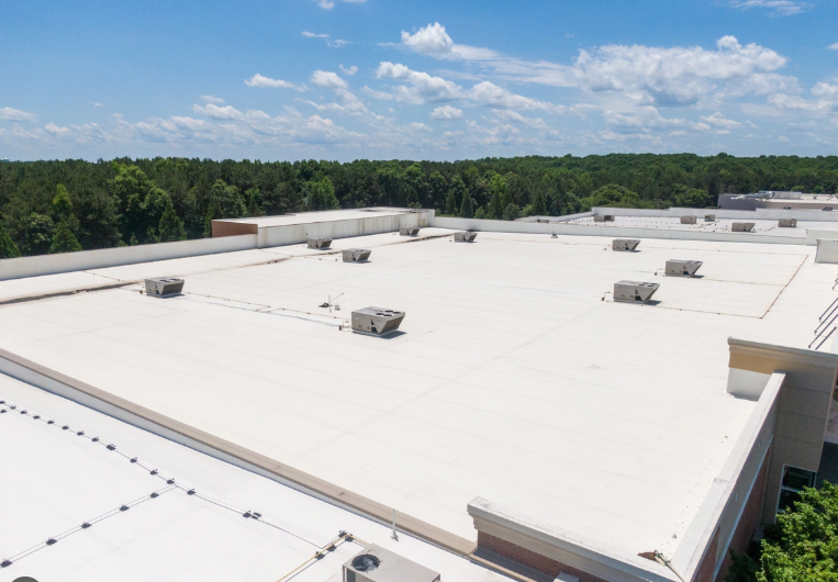 A man measuring the length of a roof with a yellow tape measure on a sunny day.