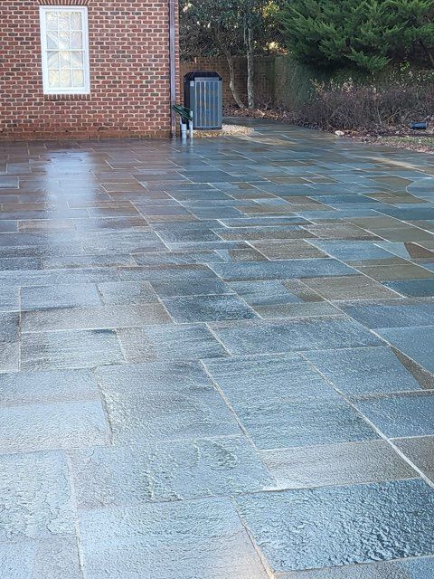 Wet, blue-gray stone patio, next to a brick building