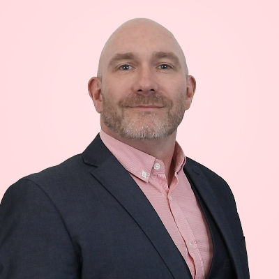 a bald man with a beard is wearing a suit and a pink shirt .
