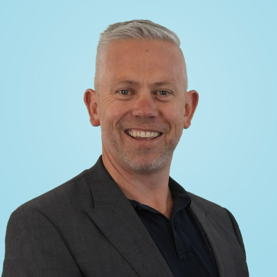 a man in a suit is smiling in front of a blue background .