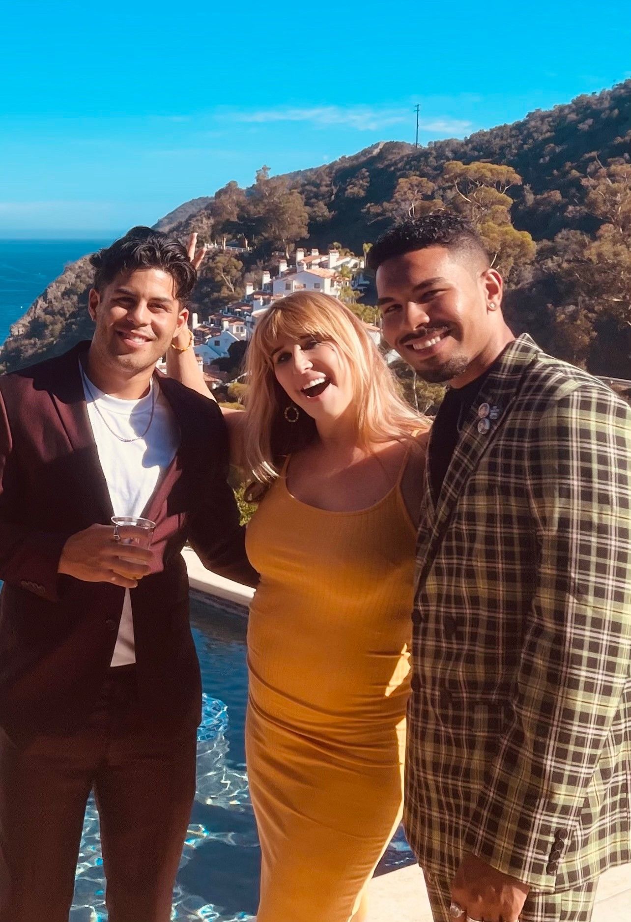 Writer Barbara Ross wears  a yellow dress and stands between two men in suits