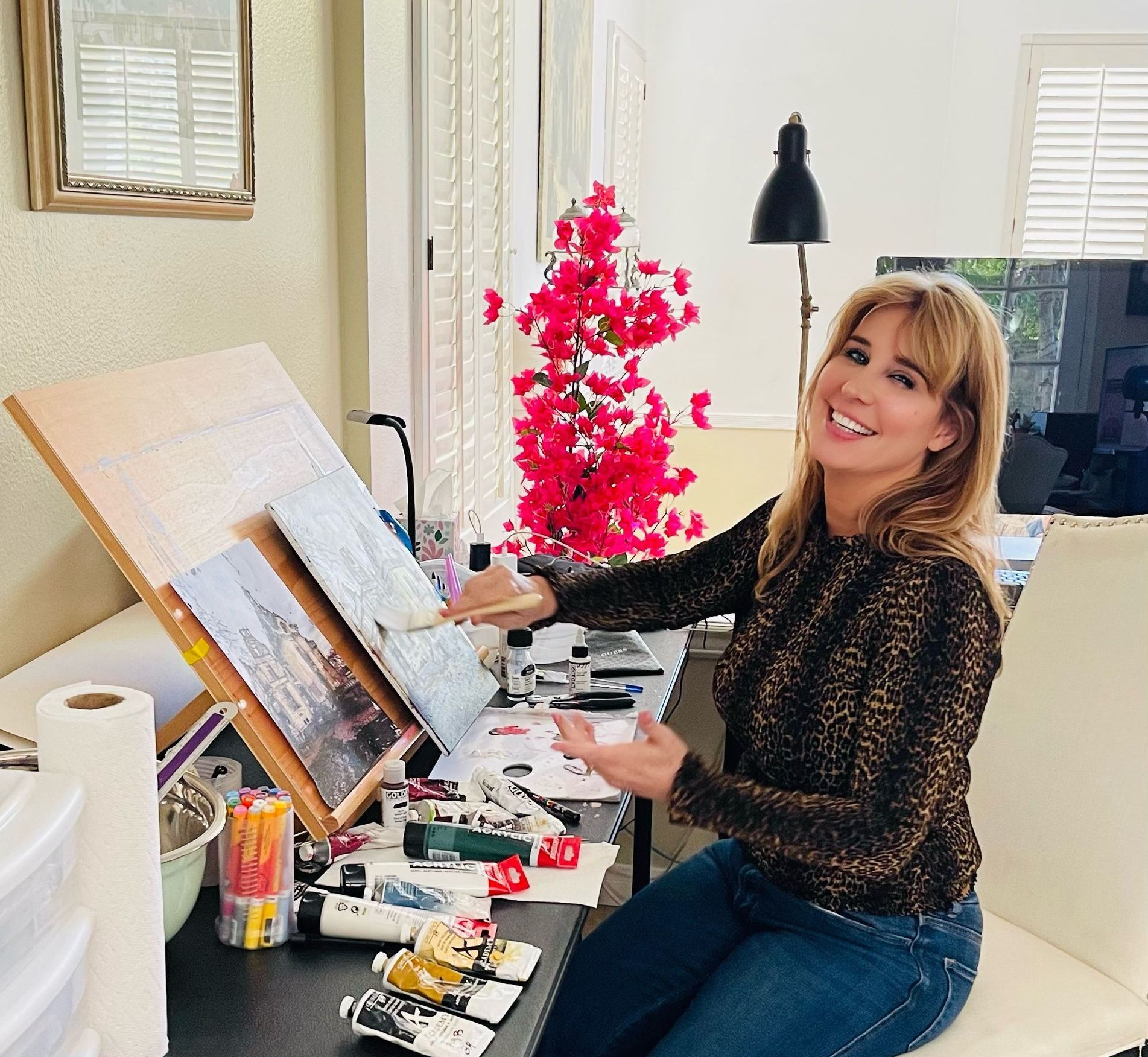 Barbara Ross is sitting at a desk painting a picture