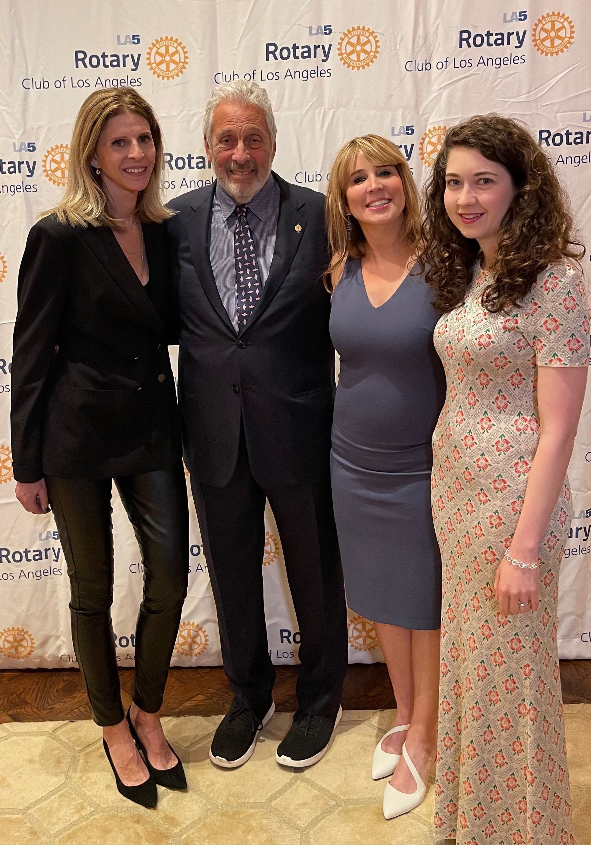 A group of people posing for a picture in front of a wall that says rotary