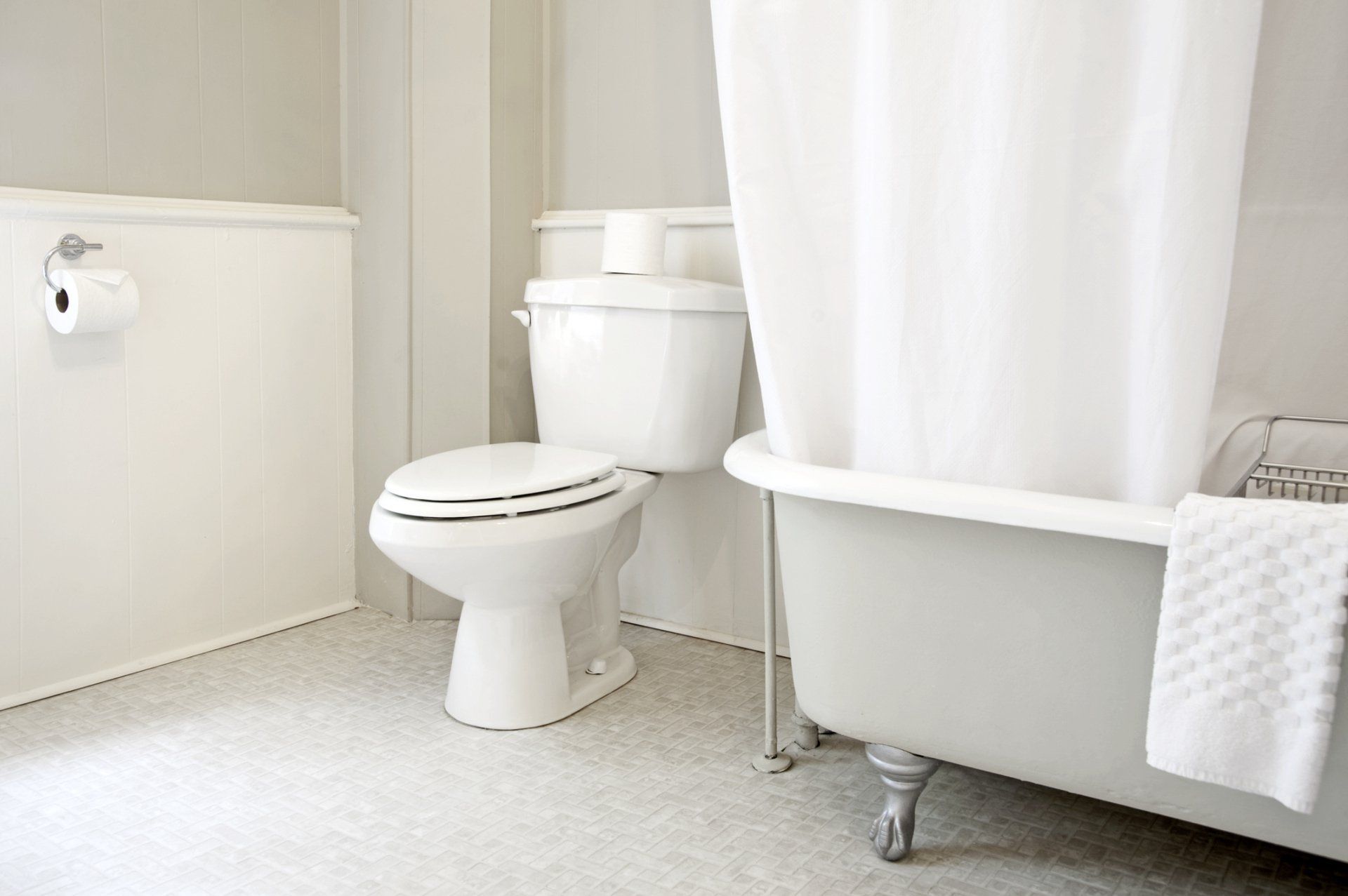 White bathroom with a toilet, bathtub, and shower curtain.
