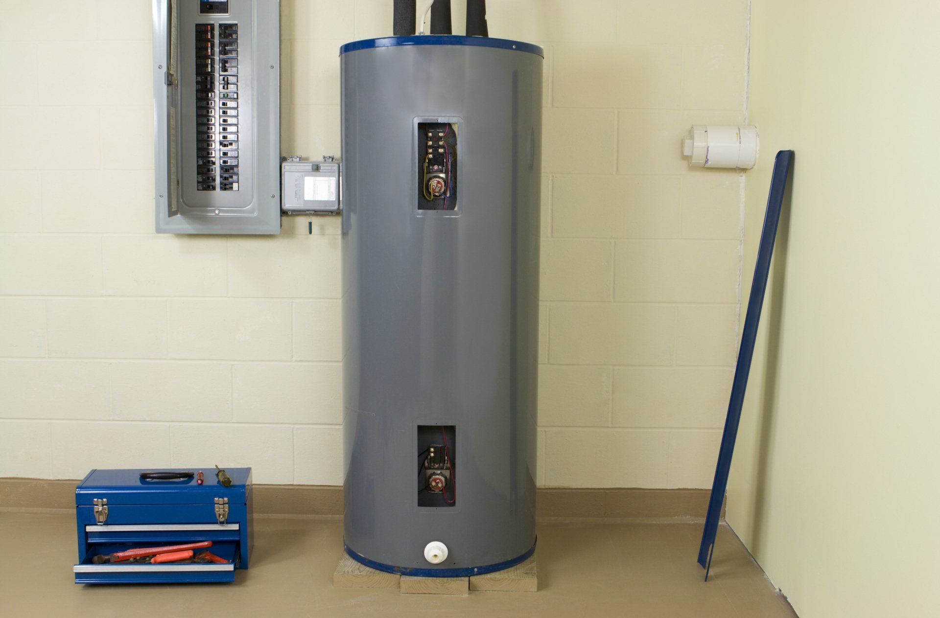 Water heater in a utility room next to a toolbox and a circuit breaker.
