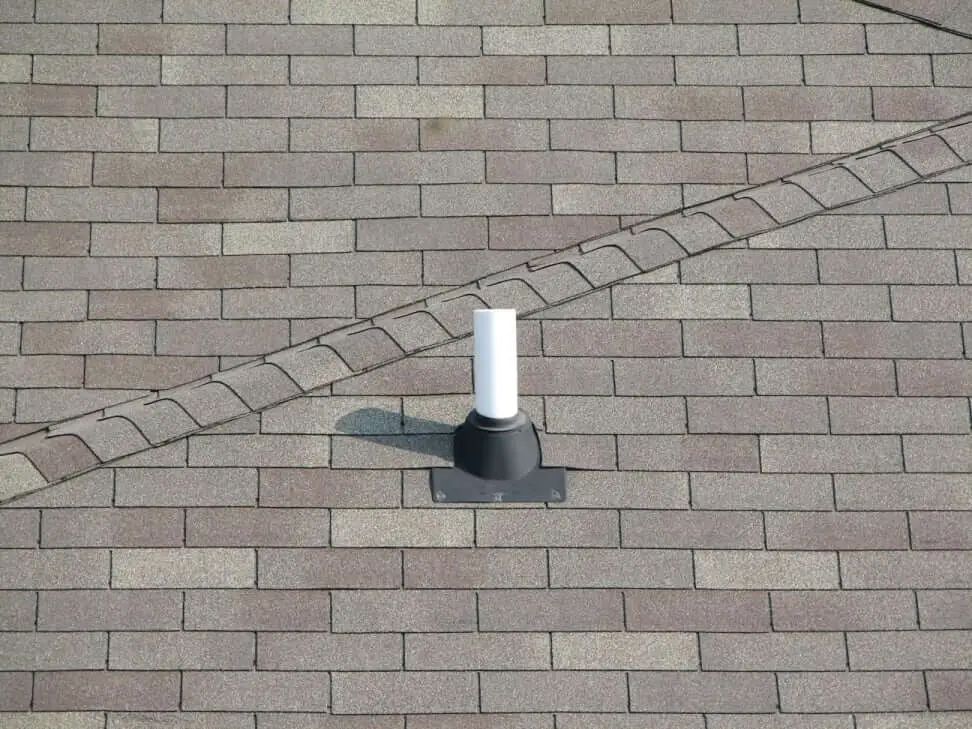 A white pipe is sitting on top of a brick roof