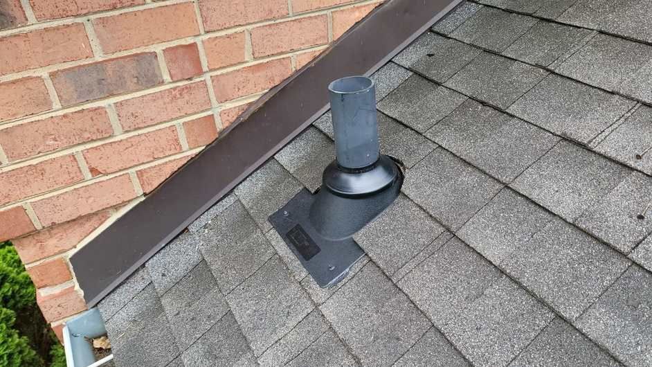A roof with a chimney on it next to a brick building.