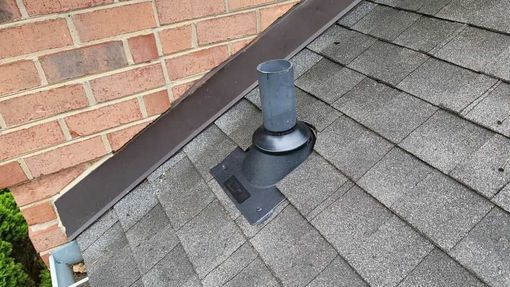 A brick chimney is on the roof of a house.