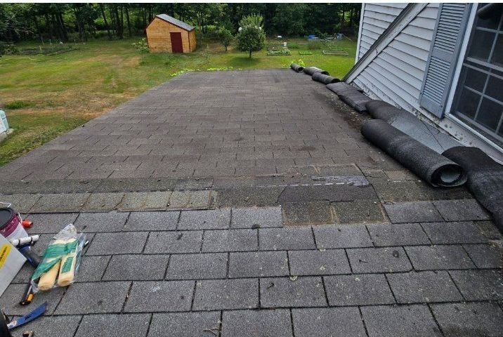 A roof of a house with a shed in the background