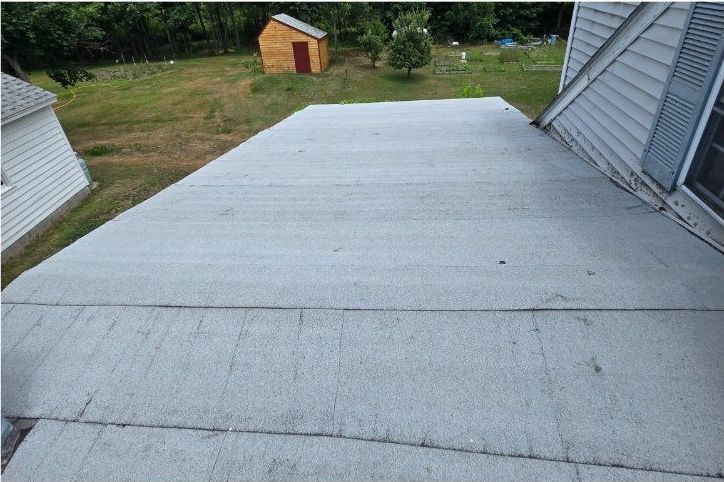 A roof of a house with a shed in the background